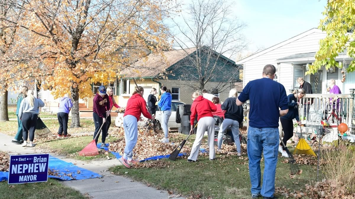 Students raking a community memebers yard